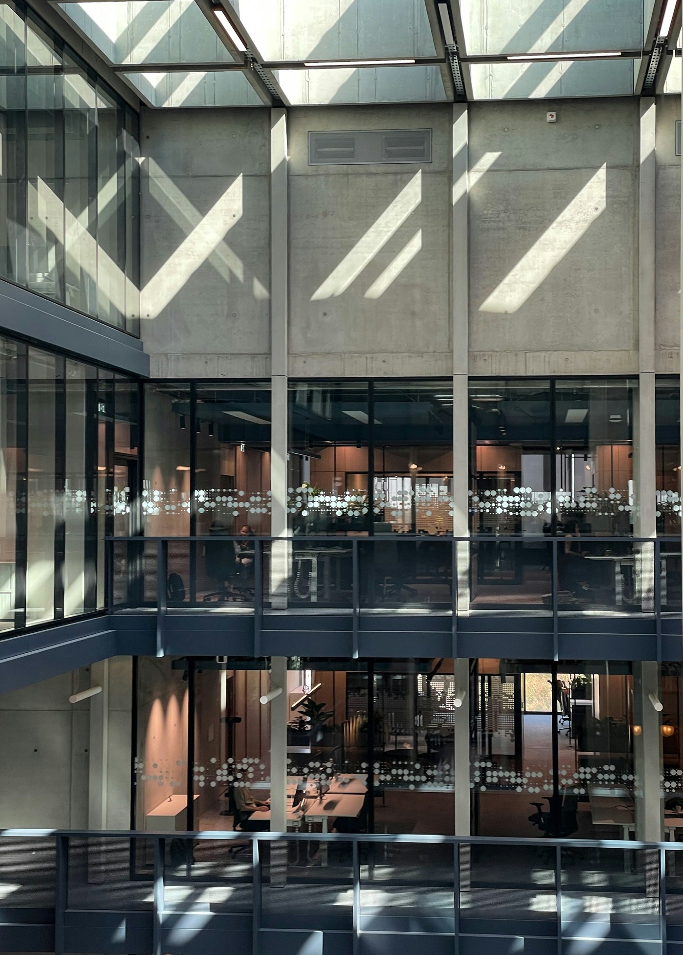 A multi-level modern workplace connected by glass, concrete, and shared infrastructure